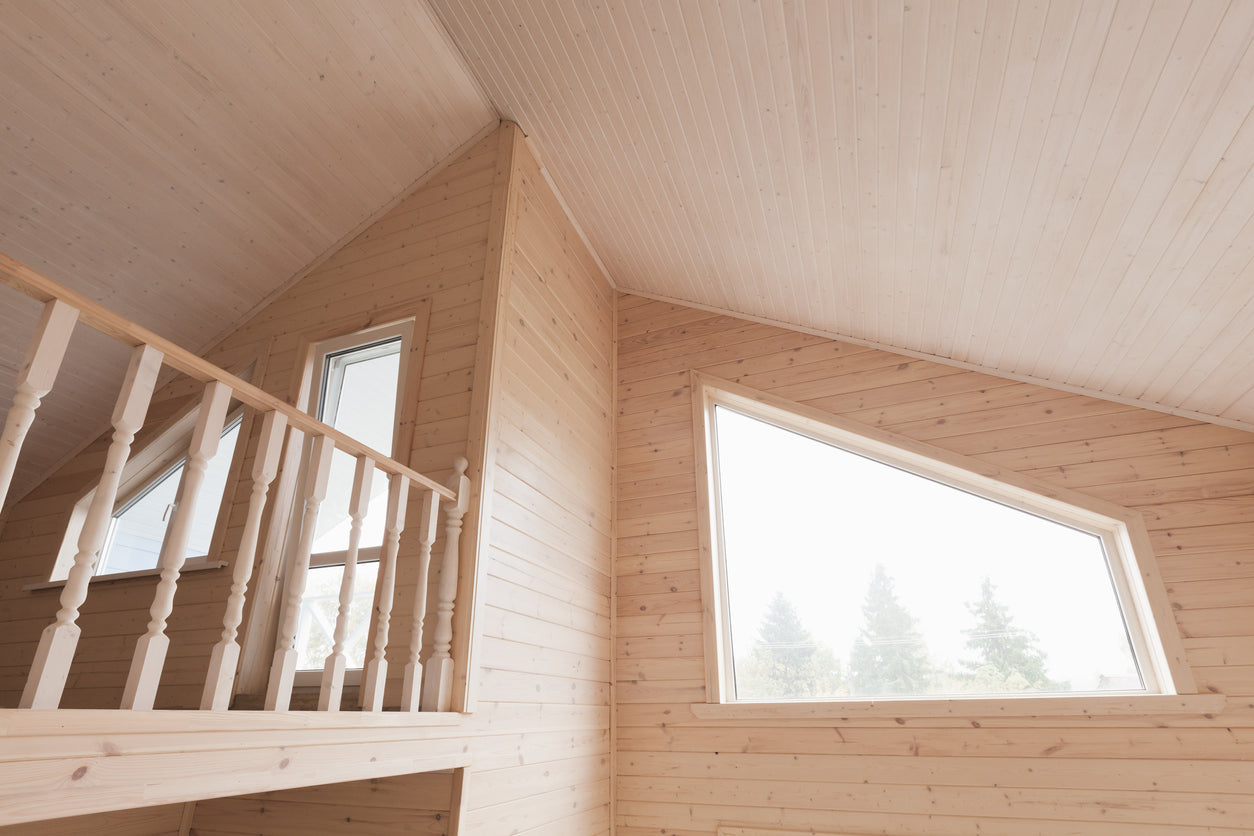 Mezzanine en bois massif avec garde-corps, bardage intérieur et grandes fenêtres triangulaires apportant une forte luminosité dans un chalet en Haute-Savoie, réalisée par La Haute Peinture.