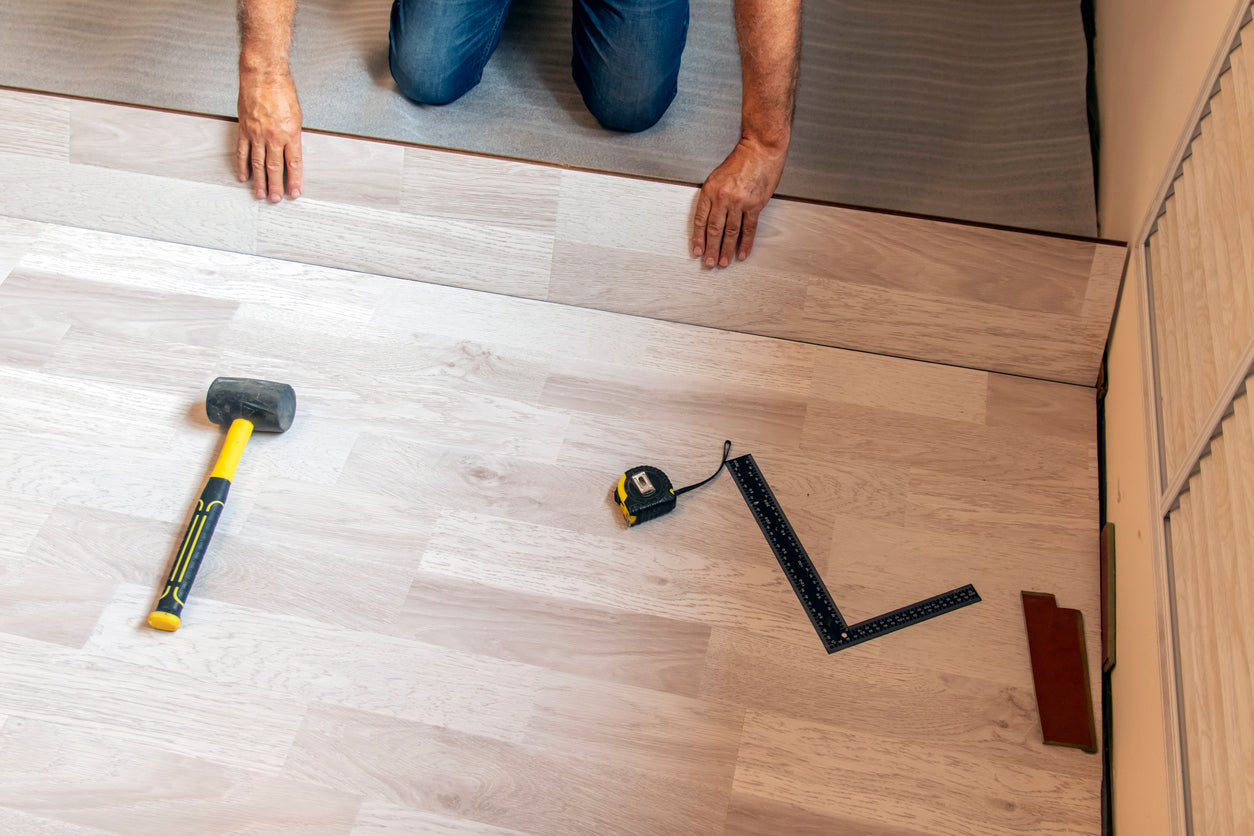 Pose d'un parquet flottant en bois clair sur sous-couche isolante dans une habitation à Thonon-les-Bains en Haute-Savoie. Installation soignée avec ajustement précis des lames pour un revêtement de sol durable et esthétique par La Haute Peinture.