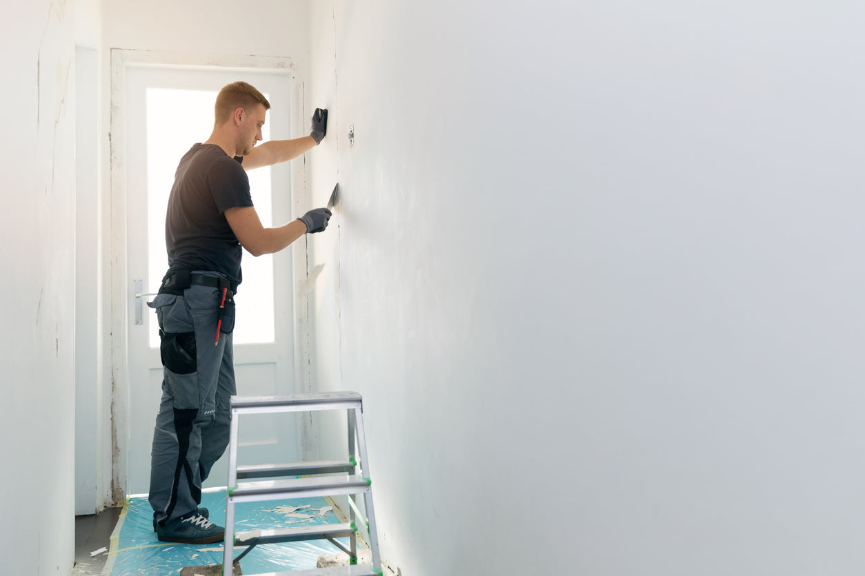 Artisan appliquant un enduit de lissage sur un mur avant peinture afin d'obtenir une surface parfaitement lisse lors d'une rénovation intérieure réalisée par La Haute Peinture en Haute-Savoie.
