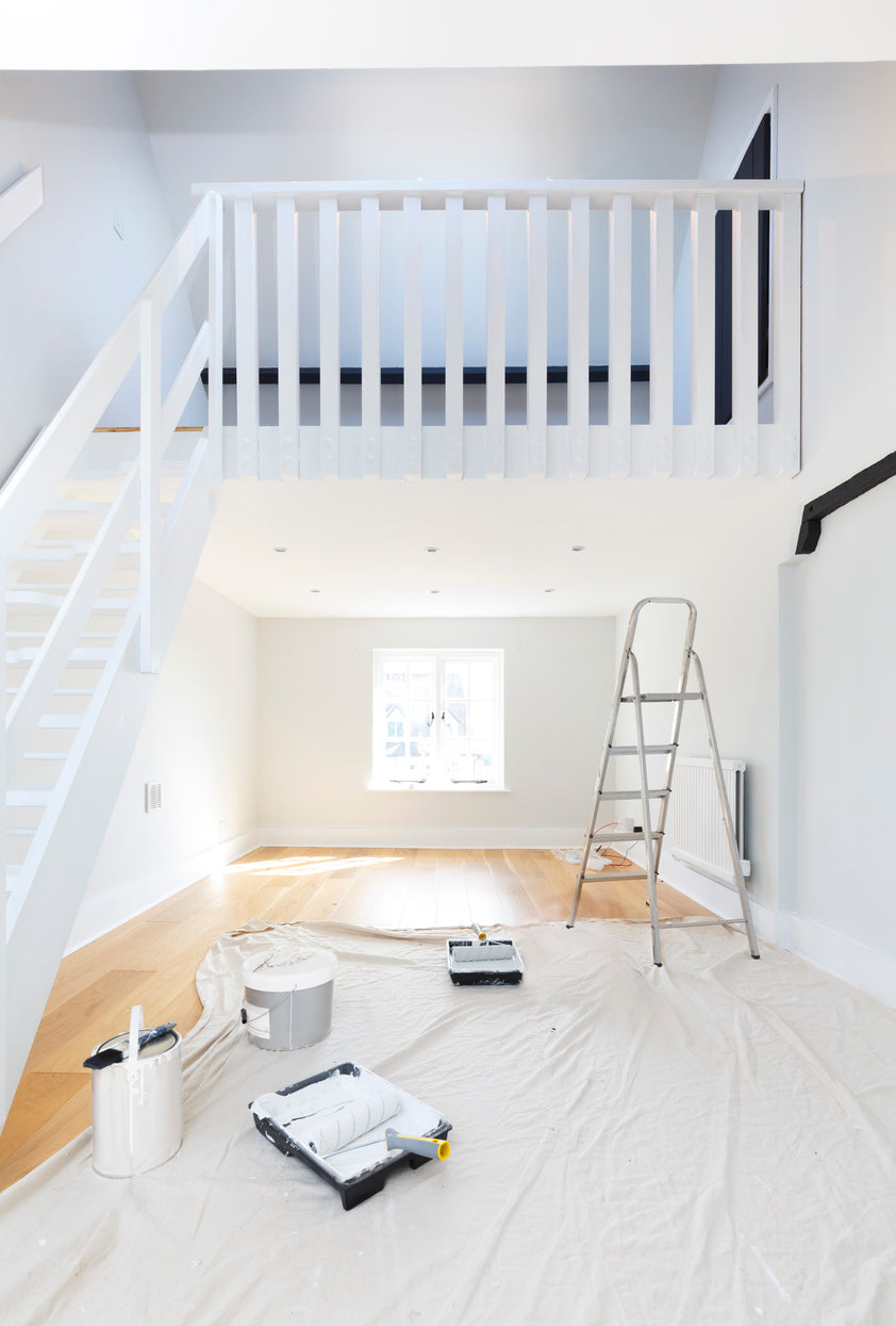 Pièce avec mezzanine et escalier en cours de finition, protégée pour les travaux de peinture avec matériel de peintre au sol, réalisée par La Haute Peinture en Haute-Savoie.