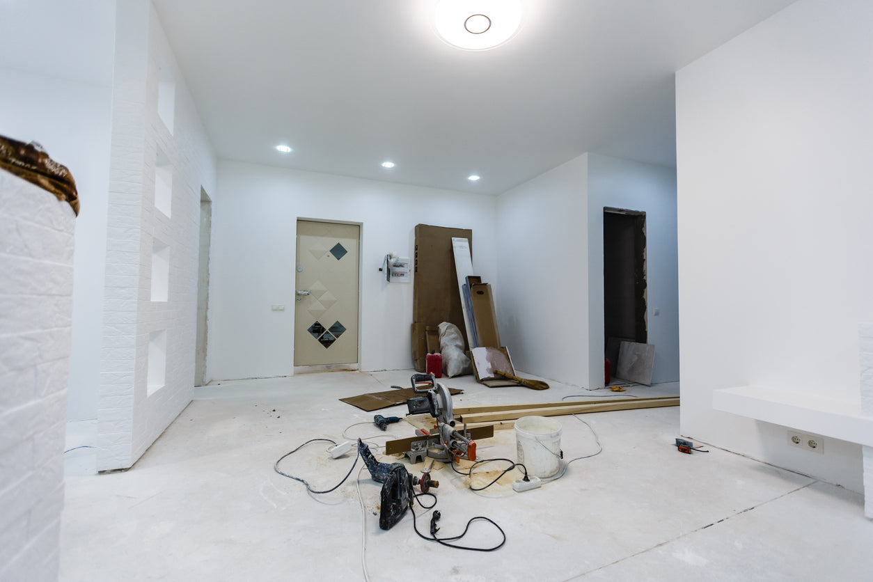 Pièce en cours de rénovation avec murs fraîchement peints, éclairage encastré installé et matériel de chantier au sol avant la pose des revêtements de sol par La Haute Peinture en Haute-Savoie.